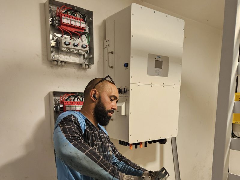 Técnico montando eletrocalha ao lado do inversor